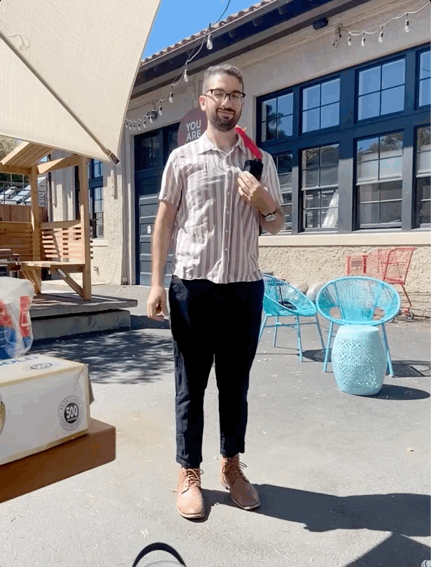 gif of eric outside smiling as a small red inflatable man dances on his shoulder